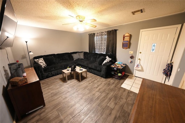 living room featuring ceiling fan, wood finished floors, and a textured ceiling