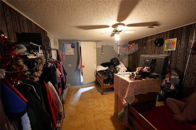 bedroom featuring a textured ceiling, wooden walls, and a ceiling fan