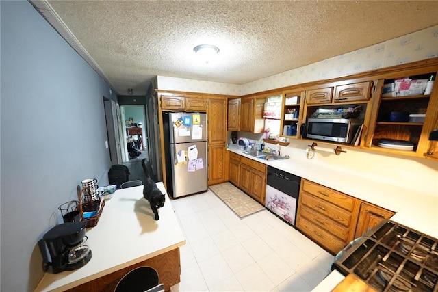 kitchen featuring stainless steel appliances, a textured ceiling, light countertops, brown cabinetry, and a sink