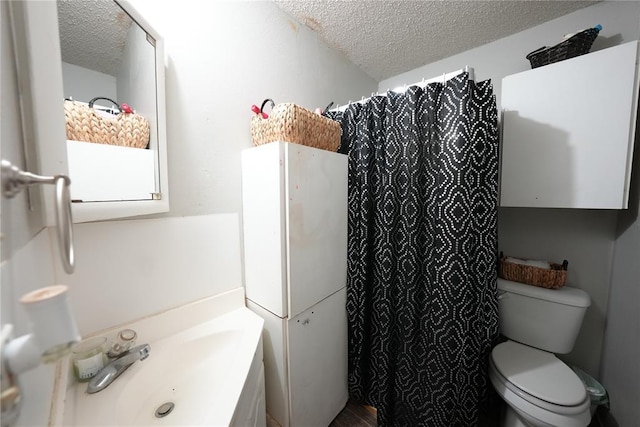 bathroom with a textured ceiling, toilet, a sink, and curtained shower