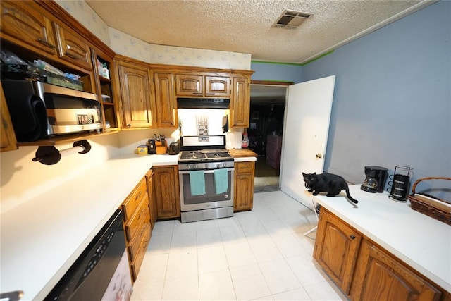 kitchen with stainless steel appliances, light countertops, brown cabinets, a textured ceiling, and extractor fan