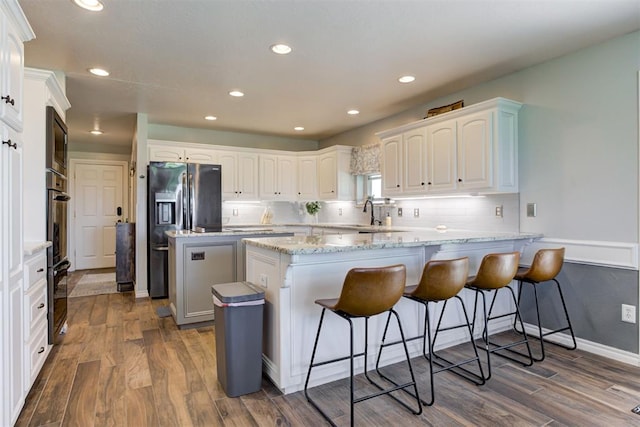 13131 SW 15th St, Yukon, OK 73099 - kitchen featuring a peninsula, dark wood finished floors, fridge with ice dispenser, a breakfast bar area, and recessed lighting