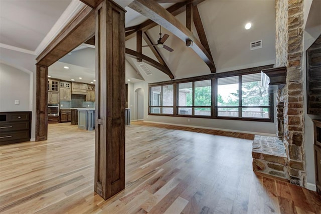 1440 Station St, Edmond, OK 73034 - unfurnished living room featuring arched walkways, beamed ceiling, light wood finished floors, baseboards, and high vaulted ceiling