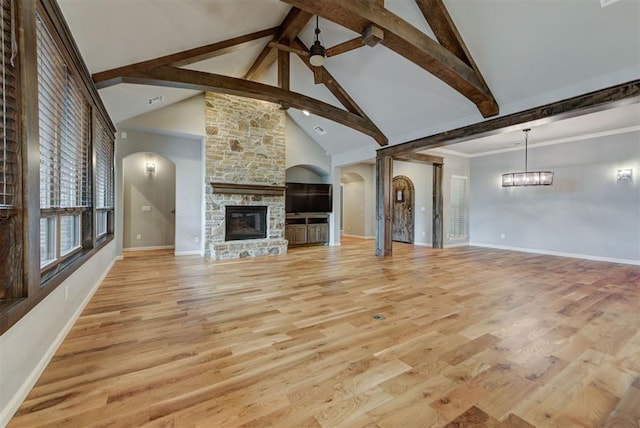 1440 Station St, Edmond, OK 73034 - unfurnished living room with a stone fireplace, beamed ceiling, arched walkways, light wood finished floors, and high vaulted ceiling