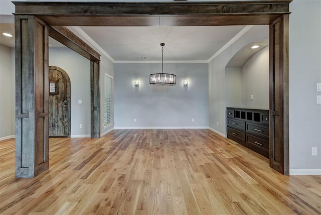 1440 Station St, Edmond, OK 73034 - unfurnished dining area with ornamental molding, baseboards, light wood-style flooring, a chandelier, and arched walkways