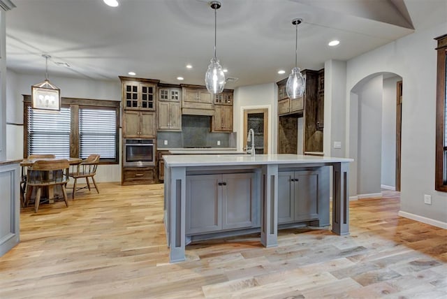 1440 Station St, Edmond, OK 73034 - kitchen with stainless steel oven, arched walkways, light countertops, light wood-type flooring, and baseboards