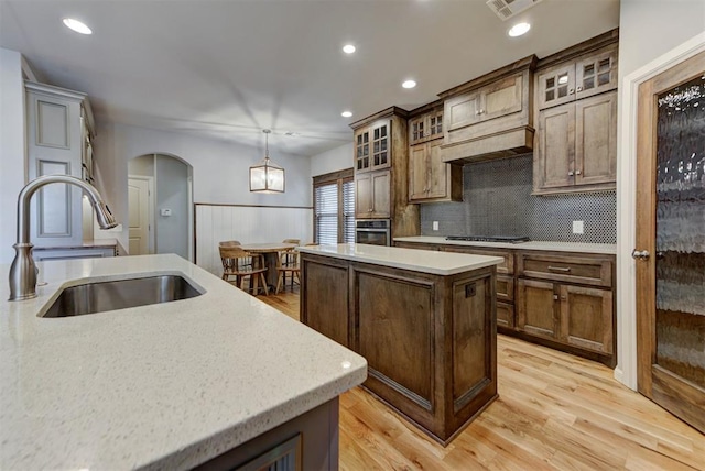 1440 Station St, Edmond, OK 73034 - kitchen with oven, a center island, arched walkways, a sink, and light countertops