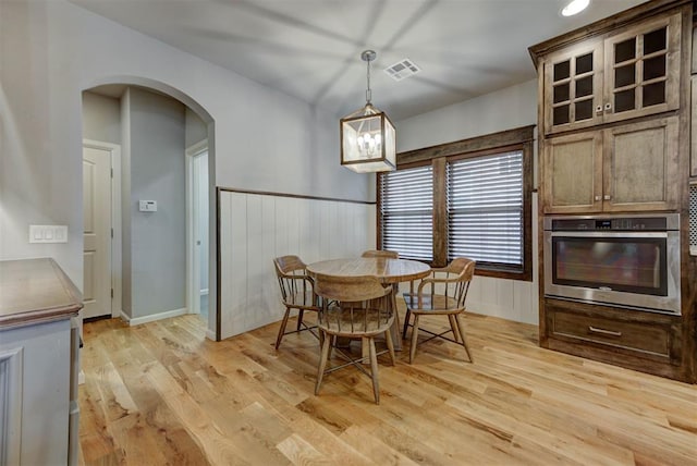 1440 Station St, Edmond, OK 73034 - dining area with arched walkways, light wood-style floors, and wainscoting