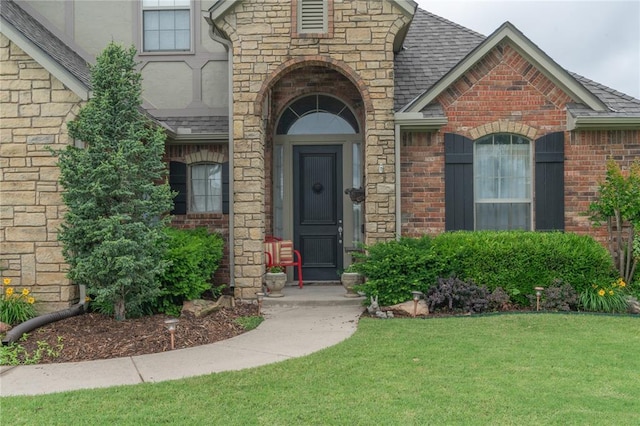 13605 Verona Strada, Oklahoma City, OK 73170 - view of exterior entry with brick siding, a lawn, and a shingled roof