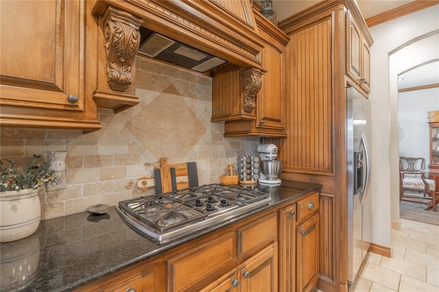 13605 Verona Strada, Oklahoma City, OK 73170 - kitchen with stainless steel appliances, arched walkways, tasteful backsplash, brown cabinets, and crown molding
