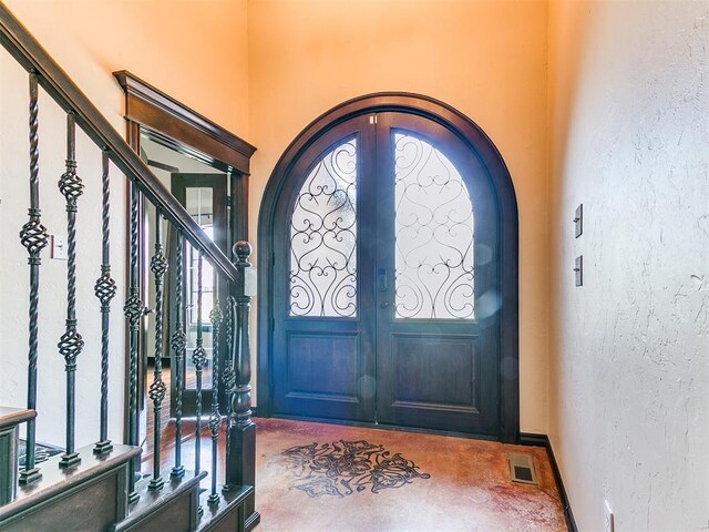 15228 Turtle Lake Pl, Oklahoma City, OK 73165 - foyer featuring concrete floors, french doors, arched walkways, stairs, and a textured wall