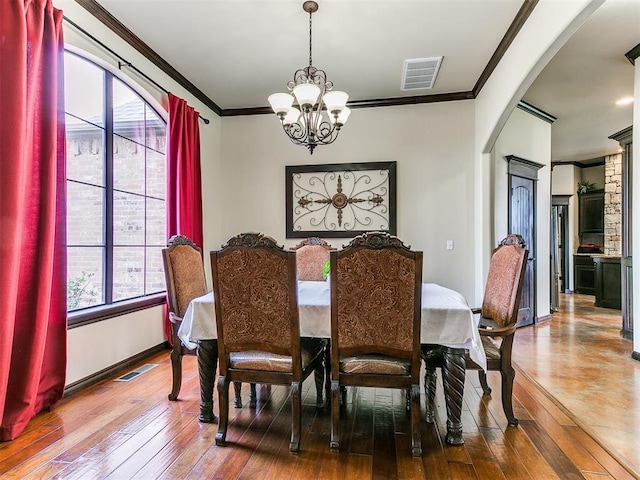 15228 Turtle Lake Pl, Oklahoma City, OK 73165 - dining area featuring a chandelier, crown molding, arched walkways, wood-type flooring, and baseboards