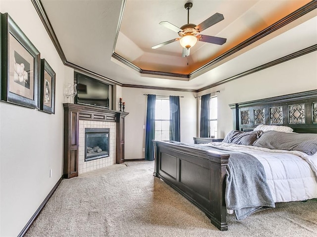 15228 Turtle Lake Pl, Oklahoma City, OK 73165 - carpeted bedroom featuring ornamental molding, a tiled fireplace, a tray ceiling, baseboards, and ceiling fan