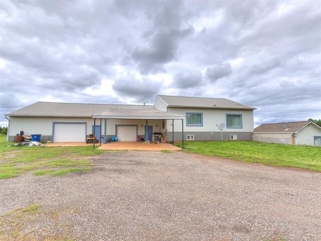 4355 S Midwest Blvd, Guthrie, OK 73044 - rear view of property featuring driveway, metal roof, a lawn, and an attached garage