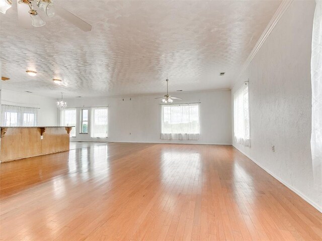 4355 S Midwest Blvd, Guthrie, OK 73044 - unfurnished living room with a ceiling fan, a chandelier, light wood-style flooring, ornamental molding, and baseboards