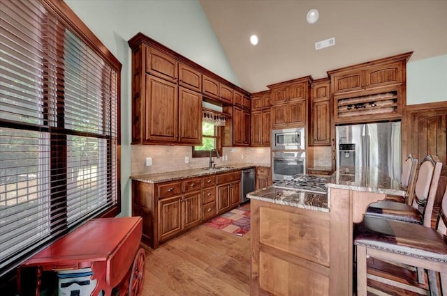 2801 John Deere Ave Unit 1, Edmond, OK 73034 - kitchen featuring stainless steel appliances, a sink, light stone counters, decorative backsplash, and a kitchen bar