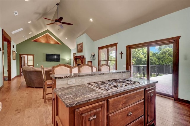 2801 John Deere Ave Unit 1, Edmond, OK 73034 - kitchen with stainless steel gas cooktop, a ceiling fan, light wood-style flooring, a kitchen island, and vaulted ceiling