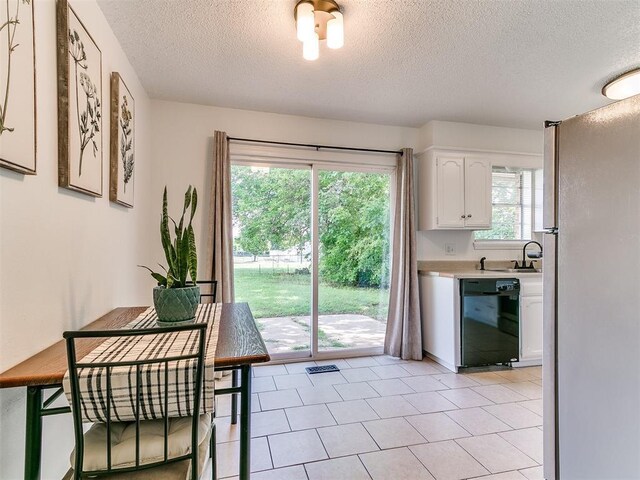 808 Robin Hill Rd, Edmond, OK 73003 - kitchen with black dishwasher, freestanding refrigerator, white cabinetry, a textured ceiling, and light countertops