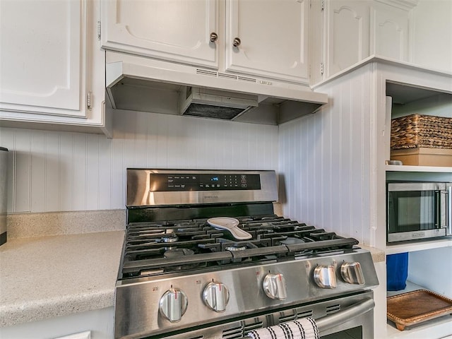 808 Robin Hill Rd, Edmond, OK 73003 - kitchen view of appliances with stainless steel finishes, white cabinetry, under cabinet range hood, and light countertops
