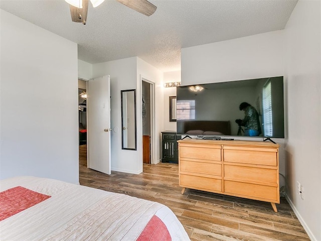808 Robin Hill Rd, Edmond, OK 73003 - bedroom with wood finished floors, a textured ceiling, baseboards, and a ceiling fan