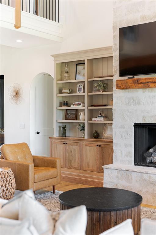 16000 N Hogback Rd, Luther, OK 73054 - living room featuring arched walkways, a fireplace with raised hearth, wood finished floors, and a high ceiling