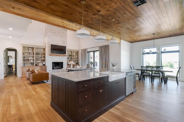 16000 N Hogback Rd, Luther, OK 73054 - kitchen with a sink, dishwasher, arched walkways, dark brown cabinets, and a stone fireplace