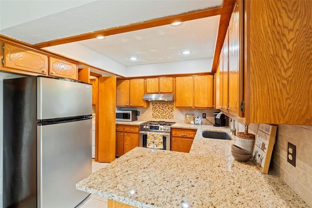 2016 Castle Rock, Edmond, OK 73003 - kitchen with appliances with stainless steel finishes, under cabinet range hood, a sink, a peninsula, and brown cabinets