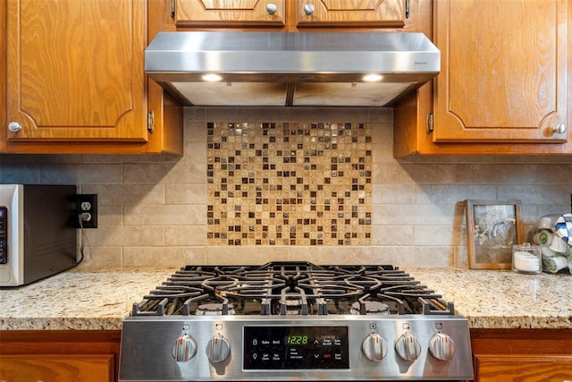 2016 Castle Rock, Edmond, OK 73003 - kitchen with stainless steel range with gas cooktop, under cabinet range hood, brown cabinets, and decorative backsplash
