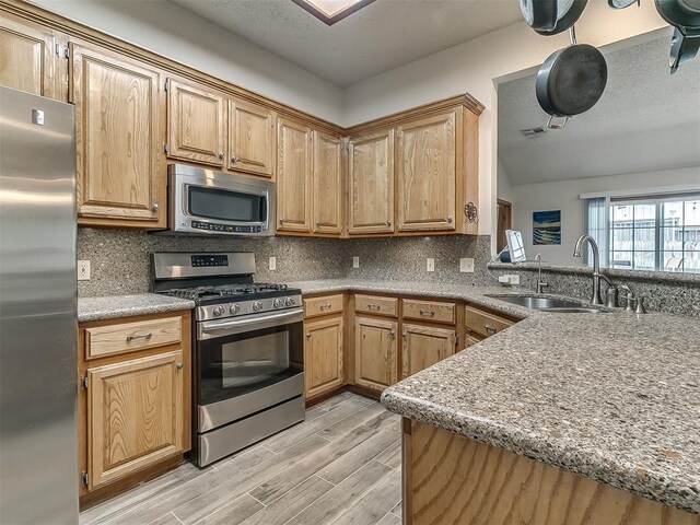 1813 Richard Dr, Edmond, OK 73003 - kitchen with appliances with stainless steel finishes, a sink, tasteful backsplash, light wood finished floors, and a textured ceiling