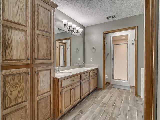 1813 Richard Dr, Edmond, OK 73003 - bathroom with a textured ceiling, toilet, a stall shower, wood finished floors, and double vanity
