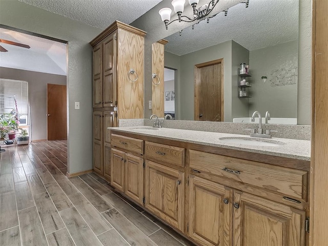 1813 Richard Dr, Edmond, OK 73003 - bathroom with double vanity, a textured ceiling, wood finished floors, a chandelier, and a ceiling fan