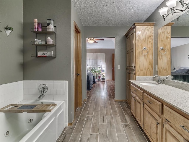 1813 Richard Dr, Edmond, OK 73003 - ensuite bathroom featuring a tub with jets, vanity, wood finished floors, ceiling fan, and a textured ceiling