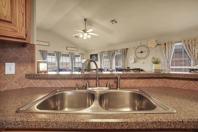 3224 Peacock Ln, Altus, OK 73521 - kitchen featuring a sink, brown cabinetry, ceiling fan, tasteful backsplash, and dark countertops