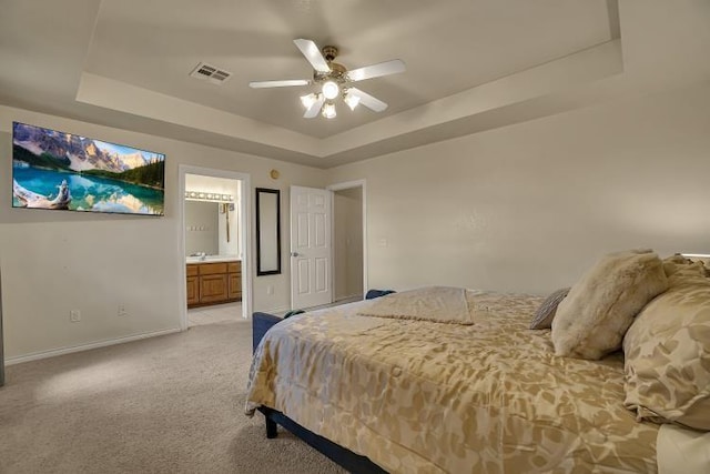 3224 Peacock Ln, Altus, OK 73521 - bedroom featuring a tray ceiling, light colored carpet, baseboards, connected bathroom, and a ceiling fan