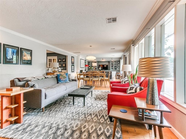 203 N Sherry Ave, Norman, OK 73069 - living area with healthy amount of natural light, crown molding, a textured ceiling, wood finished floors, and baseboards