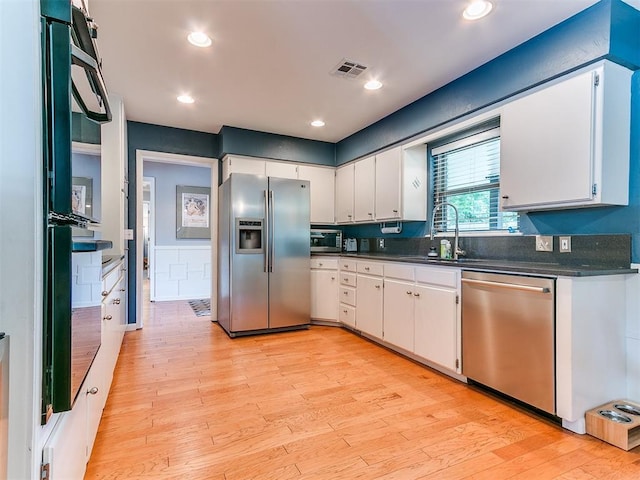203 N Sherry Ave, Norman, OK 73069 - kitchen featuring stainless steel appliances, a sink, dark countertops, light wood-style flooring, and white cabinets