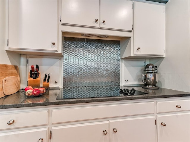 203 N Sherry Ave, Norman, OK 73069 - kitchen featuring white cabinets, dark countertops, backsplash, black electric cooktop, and under cabinet range hood