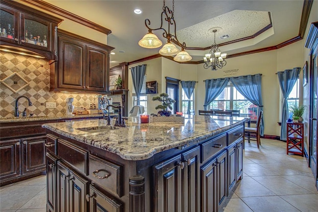 14220 SE 76th Pl, Oklahoma City, OK 73150 - kitchen with a sink, tasteful backsplash, crown molding, a center island with sink, and light stone counters