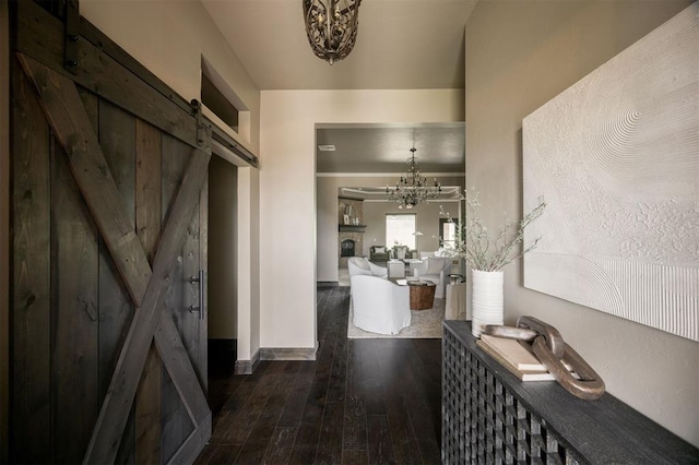 15101 Colonia Bella Dr, Edmond, OK 73013 - hall with a chandelier, a barn door, wood-type flooring, and baseboards