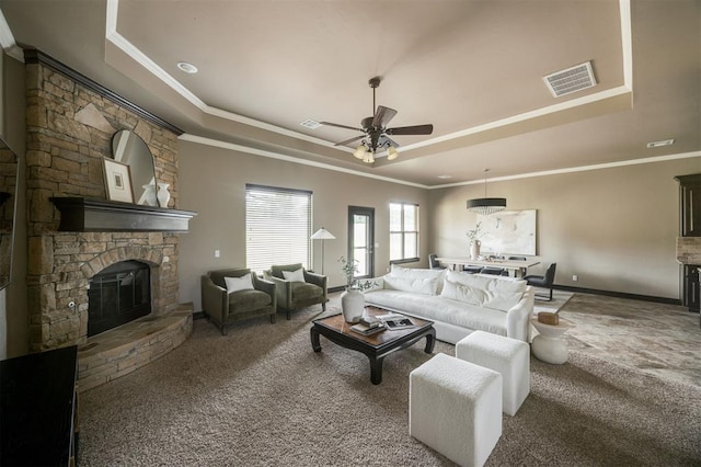 15101 Colonia Bella Dr, Edmond, OK 73013 - living area with a raised ceiling, carpet floors, a stone fireplace, ceiling fan, and ornamental molding