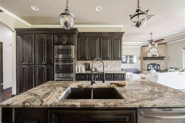 15101 Colonia Bella Dr, Edmond, OK 73013 - kitchen with stainless steel appliances, a sink, a center island with sink, a ceiling fan, and tasteful backsplash