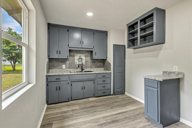 1013 Locust Ln, Midwest City, OK 73110 - kitchen featuring a sink, gray cabinets, open shelves, decorative backsplash, and plenty of natural light