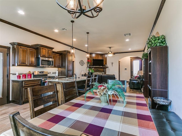 3424 Lakeside Dr, Moore, OK 73160 - dining area featuring arched walkways, ornamental molding, recessed lighting, a chandelier, and light wood-style floors