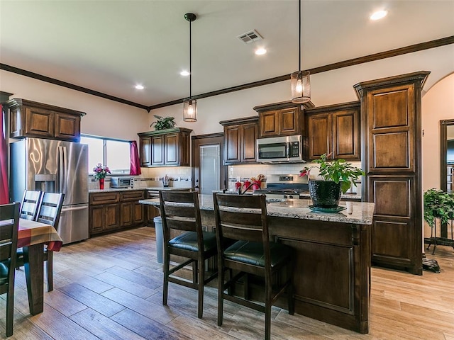 3424 Lakeside Dr, Moore, OK 73160 - kitchen featuring appliances with stainless steel finishes, dark brown cabinets, decorative backsplash, a kitchen island with sink, and ornamental molding
