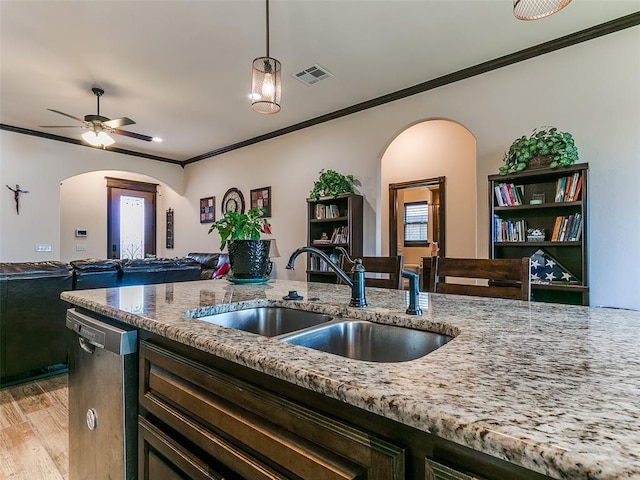3424 Lakeside Dr, Moore, OK 73160 - kitchen featuring arched walkways, a sink, open floor plan, ornamental molding, and light stone countertops