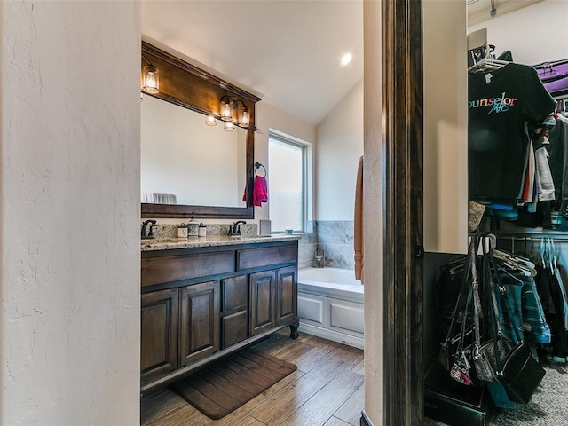 3424 Lakeside Dr, Moore, OK 73160 - bathroom featuring a bath, wood-type flooring, a walk in closet, double vanity, and lofted ceiling