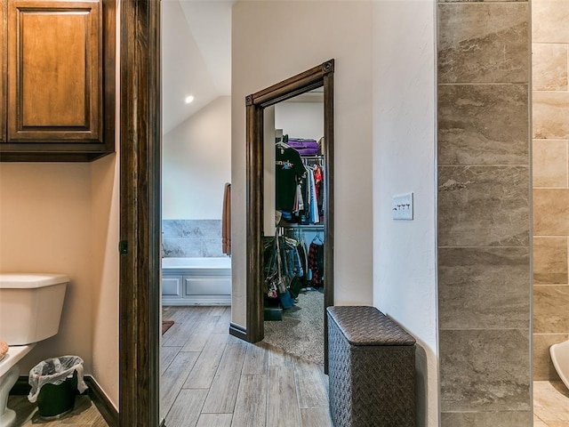 3424 Lakeside Dr, Moore, OK 73160 - full bathroom featuring a walk in closet, wood finished floors, a tub to relax in, toilet, and lofted ceiling