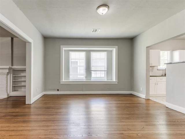 1017 N Broadway Ave, Shawnee, OK 74801 - unfurnished living room with wood finished floors, baseboards, and a sink