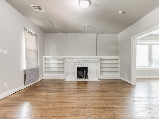1017 N Broadway Ave, Shawnee, OK 74801 - unfurnished living room featuring wood finished floors, baseboards, and a brick fireplace