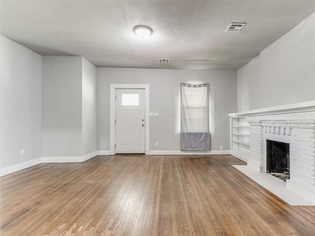 1017 N Broadway Ave, Shawnee, OK 74801 - unfurnished living room featuring wood finished floors, baseboards, and a brick fireplace